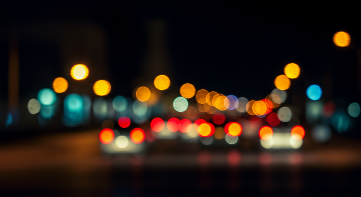 Blurry image of traffic lights and car headlights on a dark street at night, with colorful circles of light.
