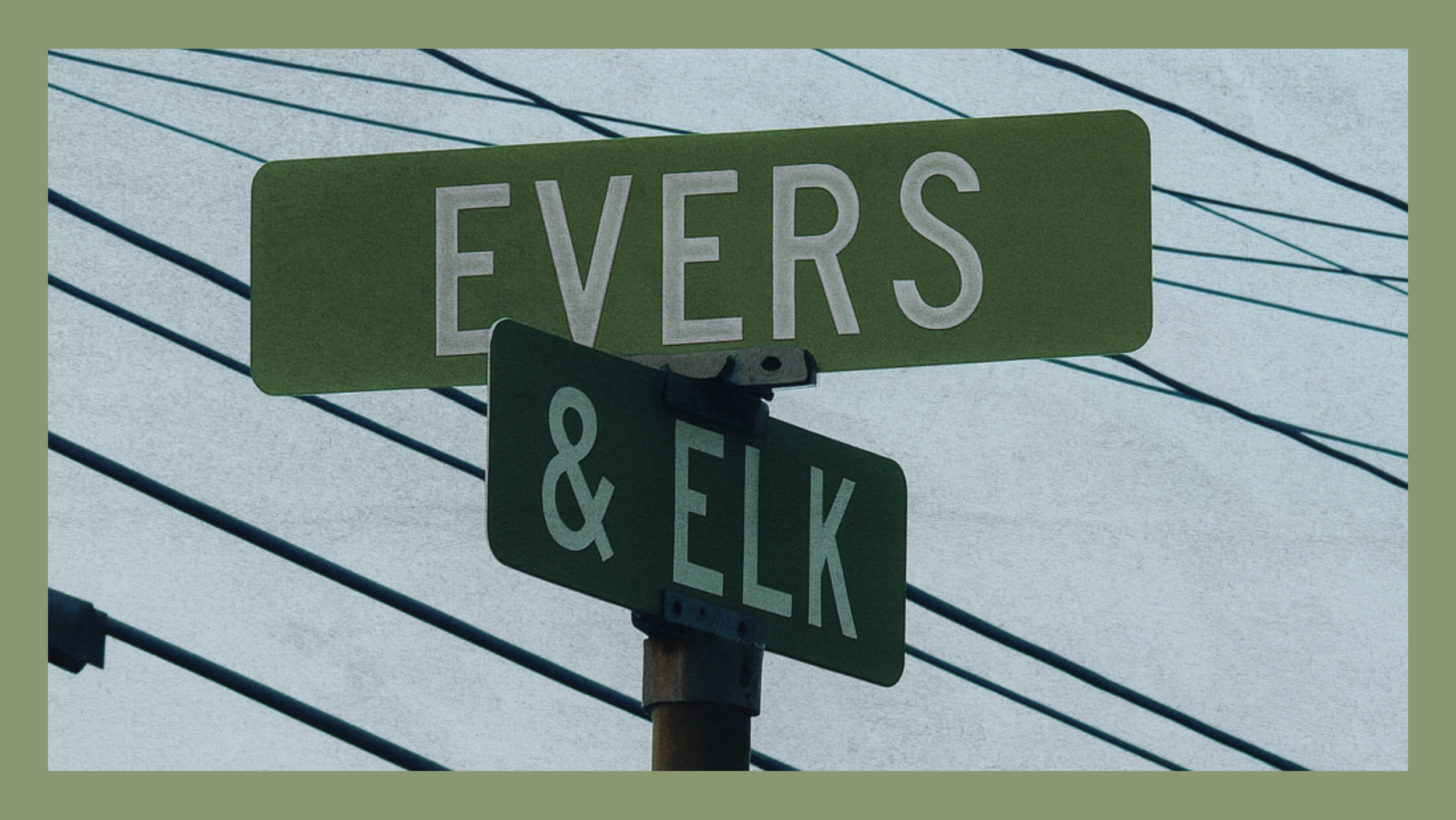 Street signs at the intersection of Evers and Elk streets, with power lines overhead, under an overcast sky.
