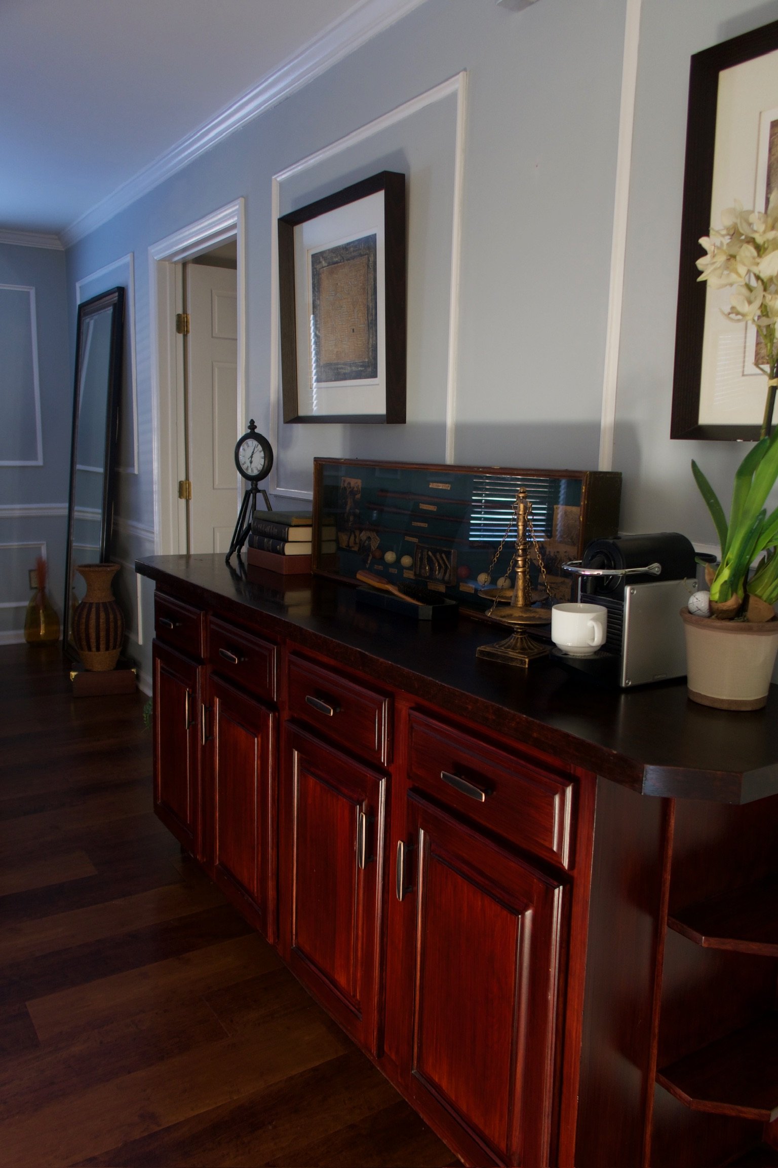 A wooden sideboard with decorative objects and framed pictures on the wall in a living room.