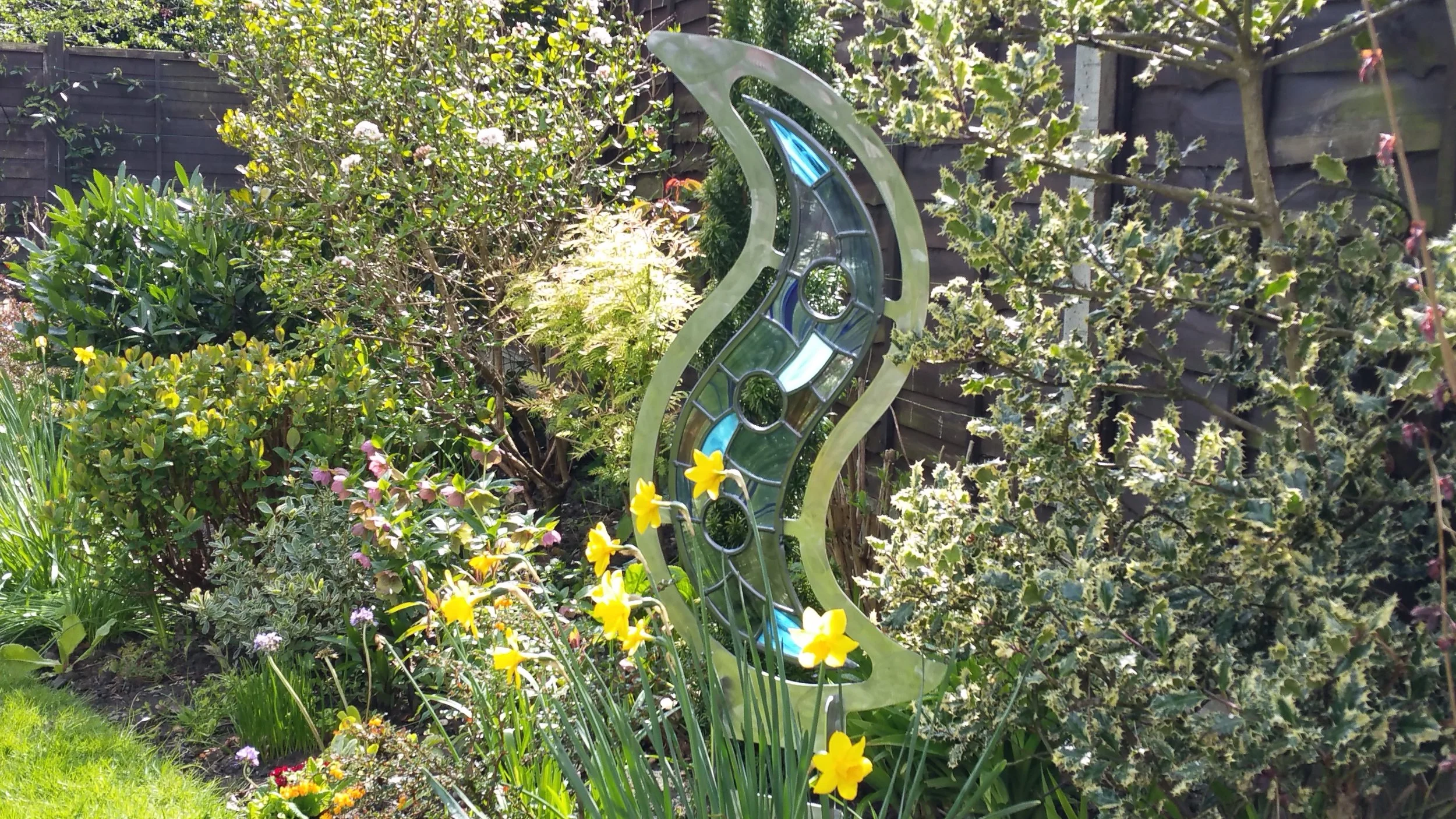Tempest Sculpture Flame art piece displayed in beautiful summer flower bed.