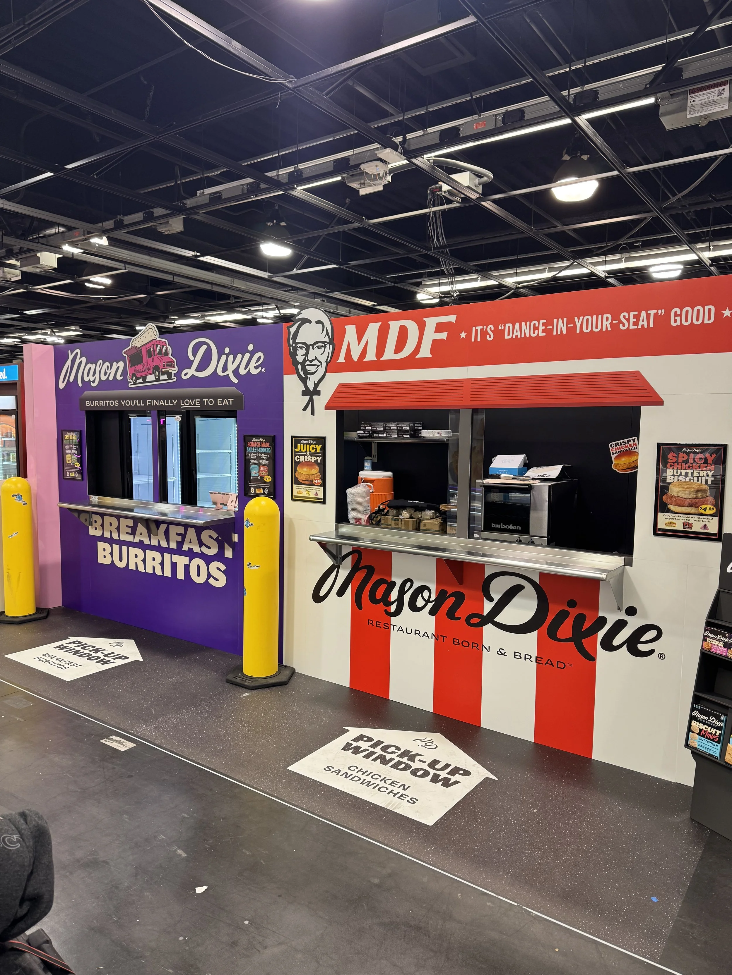 Fast food counter with Nazon Dixie branding serving breakfast burritos and chicken sandwiches, with signage indicating a pick-up window.