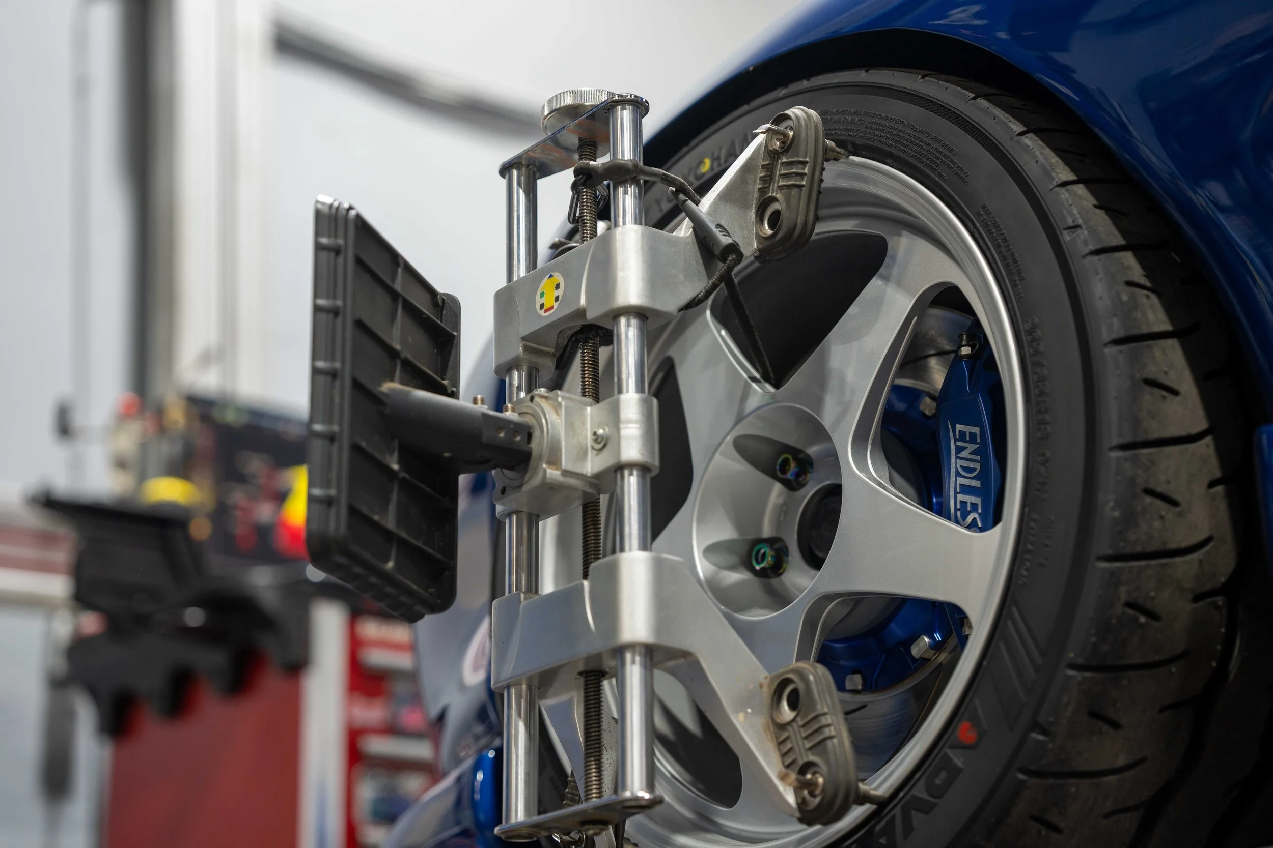 Close-up of a wheel on a race car with a wheel alignment or balancing tool attached to it.