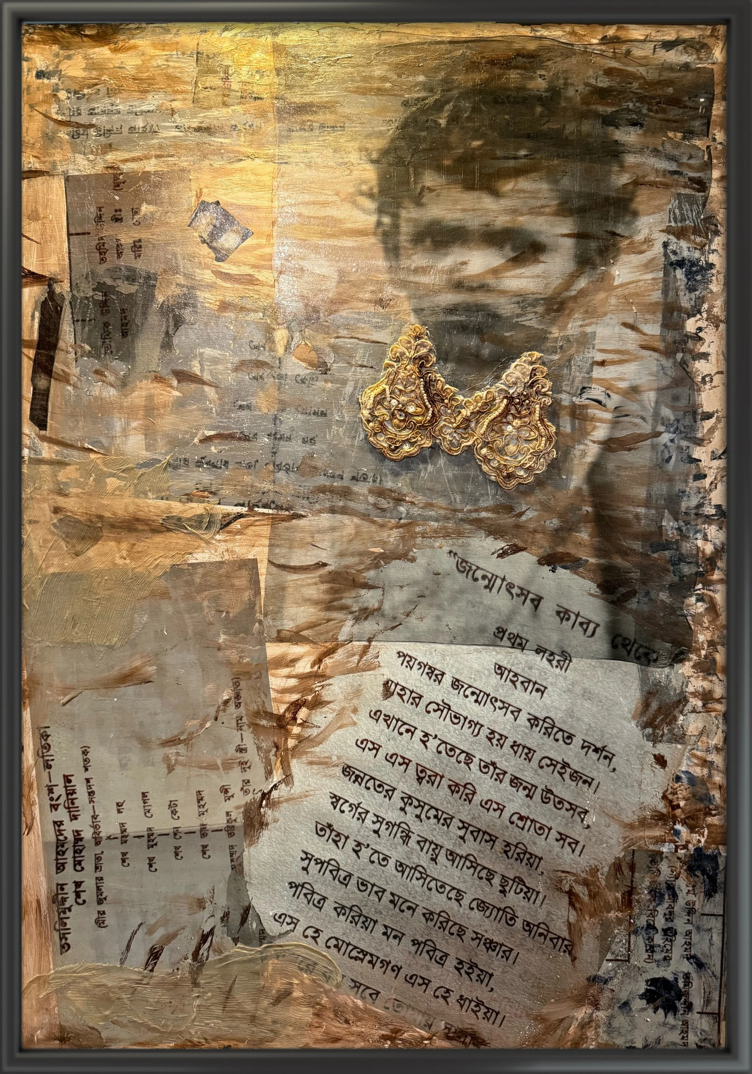 A painting with a textured background of gold, brown, and beige tones, featuring handwritten script in a language that appears to be Bengali, with gold jewelry placed on the right side of the painting.