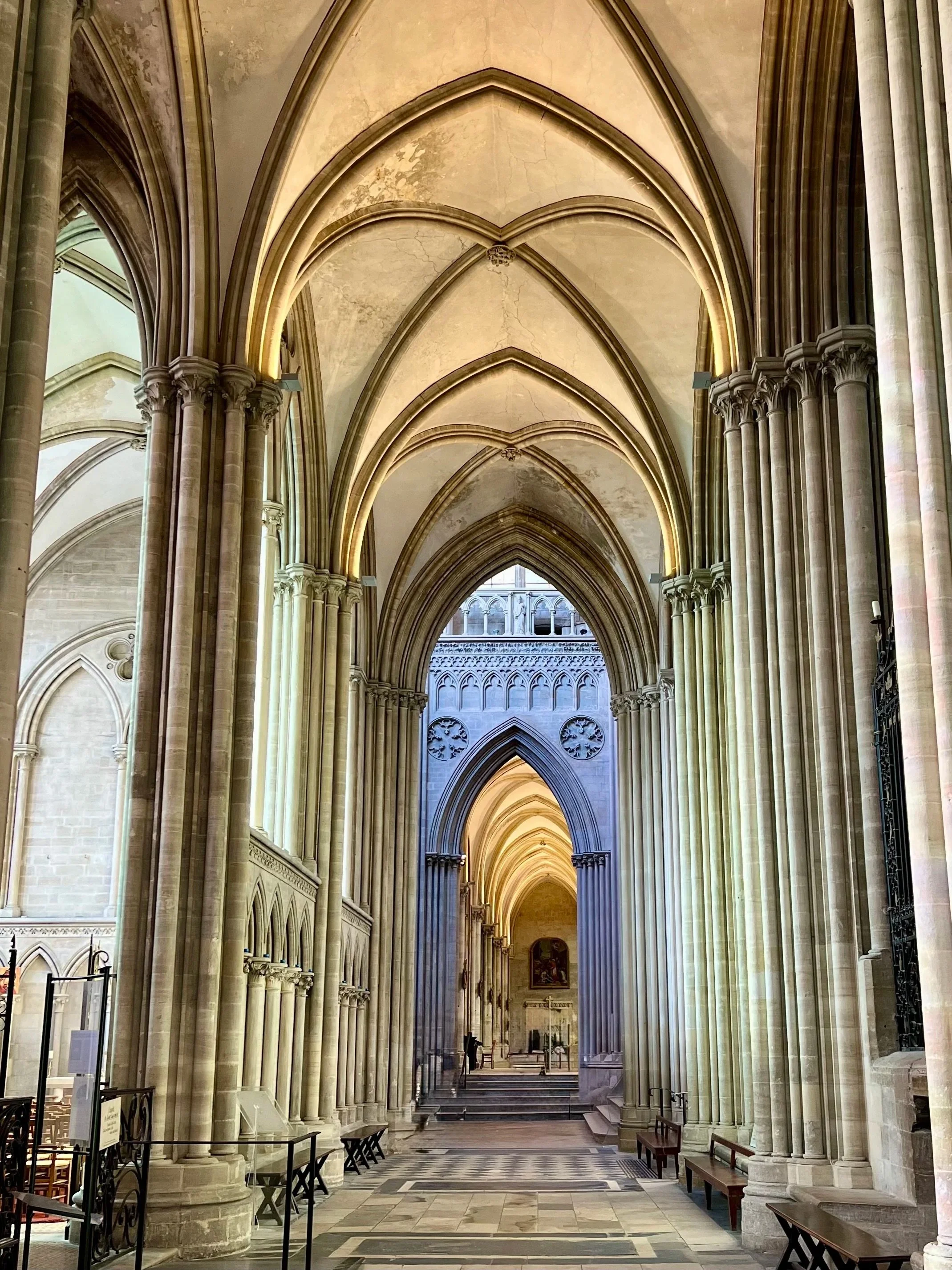 Interior of a Gothic cathedral with pointed arches, tall columns, and detailed stonework, leading to an altar at the end.