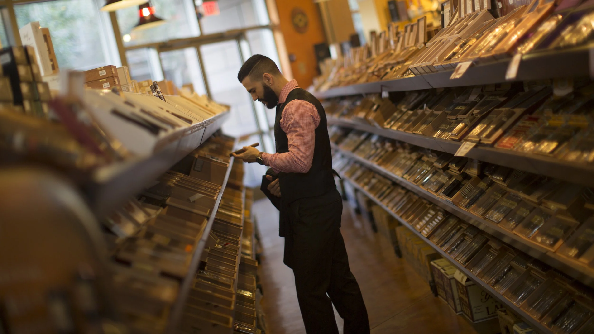 A man browsing vinyl records in a record store, holding a record in his hand, surrounded by shelves filled with albums.