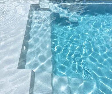 Close-up of swimming pool water with reflections and pool edge tiles.