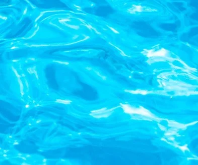 Close-up of a swimming pool's blue water surface with sunlight reflections.
