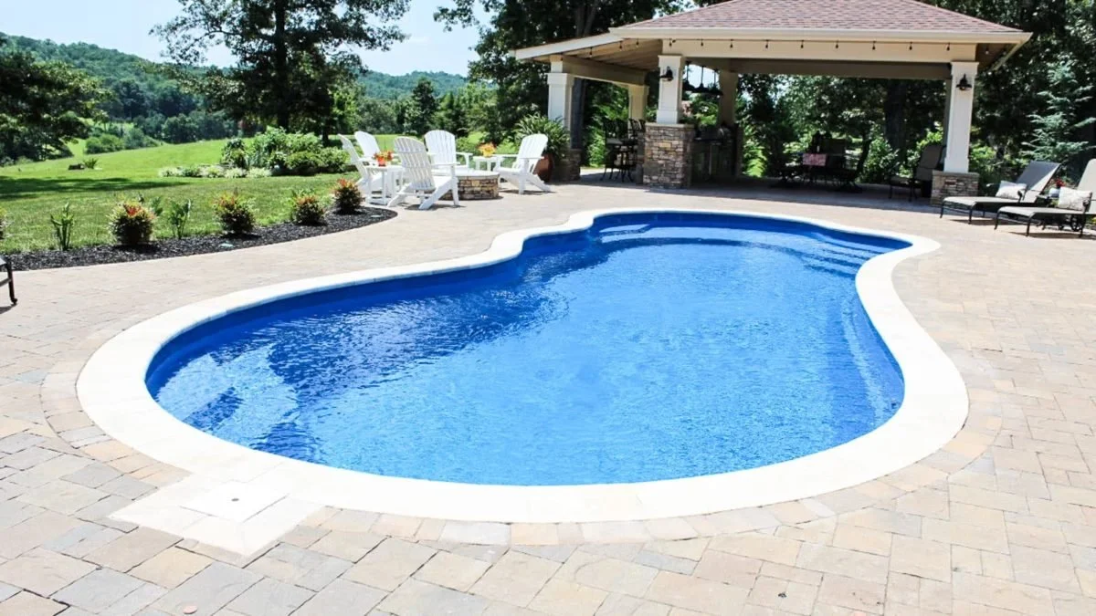 Agave Pool Company freeform fiberglass pool in East Texas with wraparound entry, built-in bench seating, and customizable lengths for elegant backyard design.