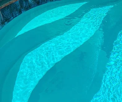 Close-up of a swimming pool with clear blue water and curved steps.