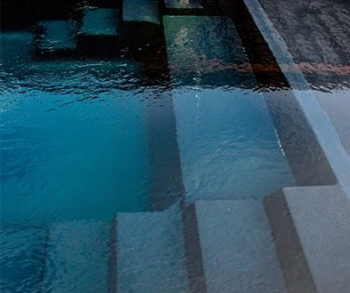 Close-up view of a swimming pool with steps and water reflections.