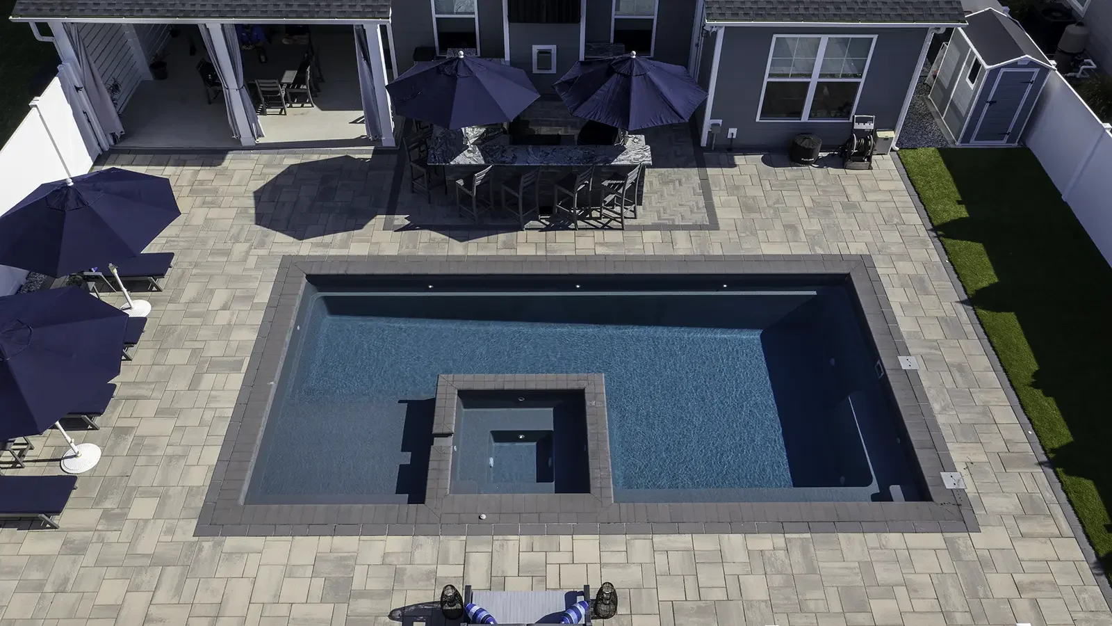 Agave Pool Company modern fiberglass pool with central spa feature and streamlined swim channel design for upscale East Texas backyard living.