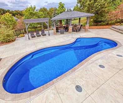 Backyard with a kidney-shaped swimming pool, two gazebos with seating, and surrounding trees and greenery.