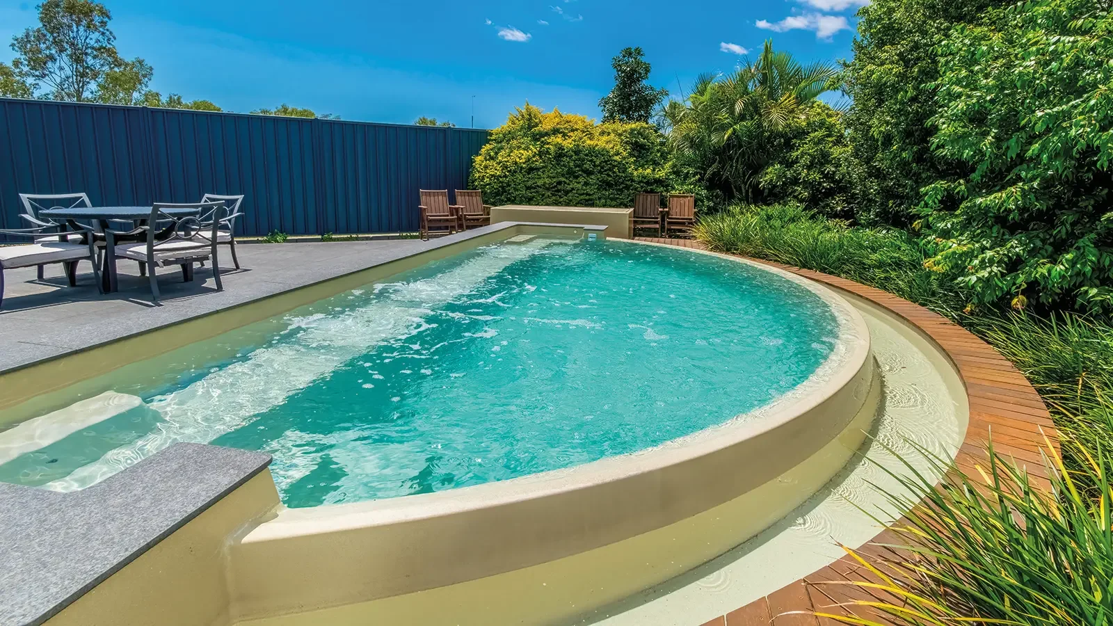 Agave Pool Company crescent-shaped fiberglass pool with spillover feature and flat-bottom design for stylish compact backyard living.