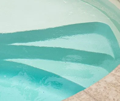 Close-up of a swimming pool with curved pool edges and light blue water