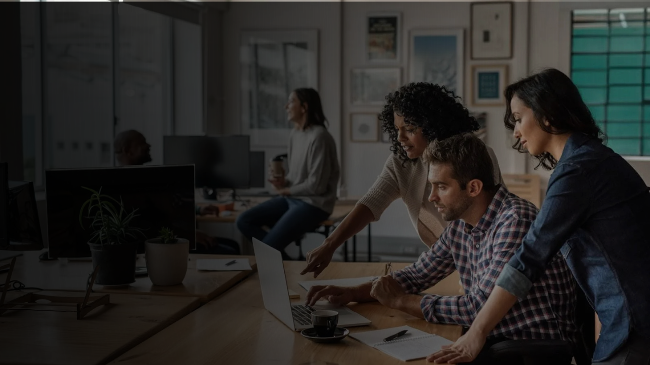 Colleagues gather round laptop