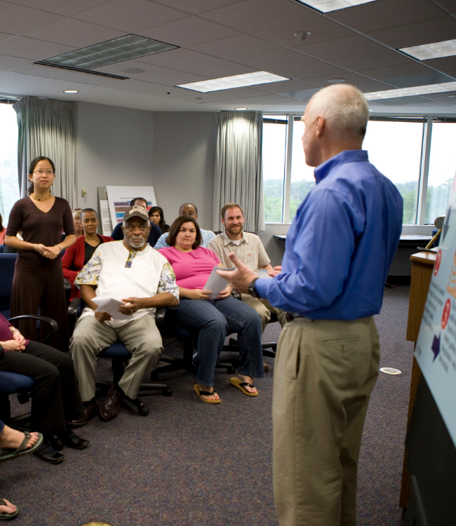 male manager talks to room of colleagues