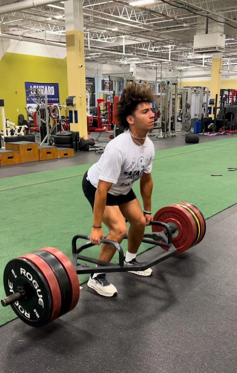A person performing a deadlift exercise with a loaded barbell at a gym.