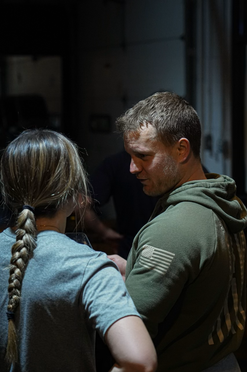 A man and a girl having a conversation, facing each other, in a dimly lit room.