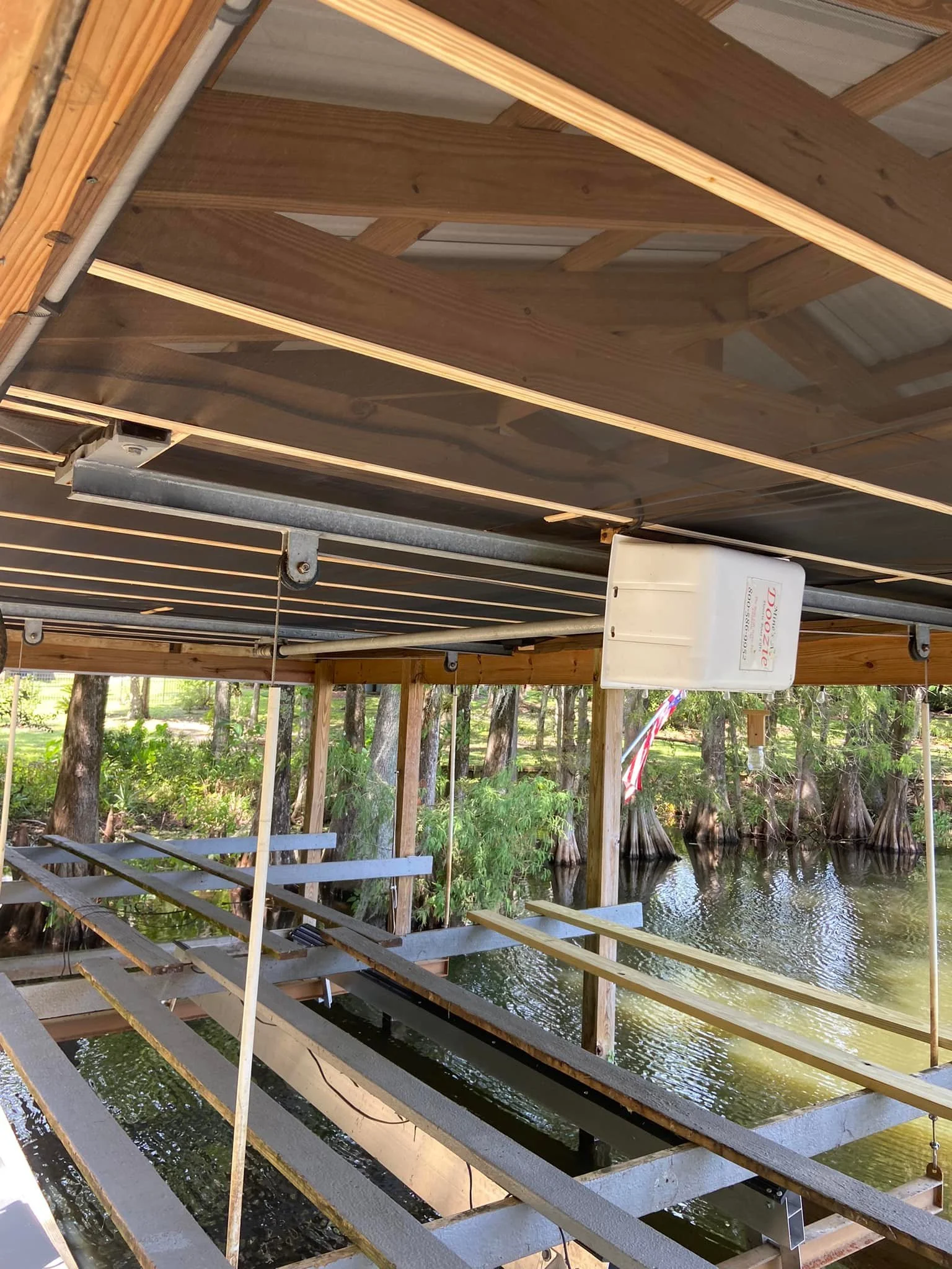 Underwater dock constructed of metal and wood, situated along a river, with cypress trees in the background.