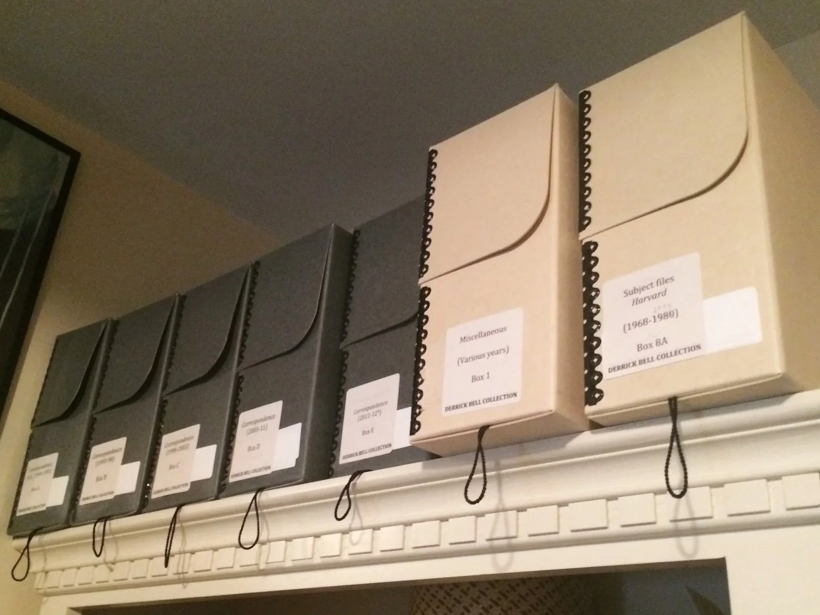 Shelf with six black and beige boxes labeled with collection information.