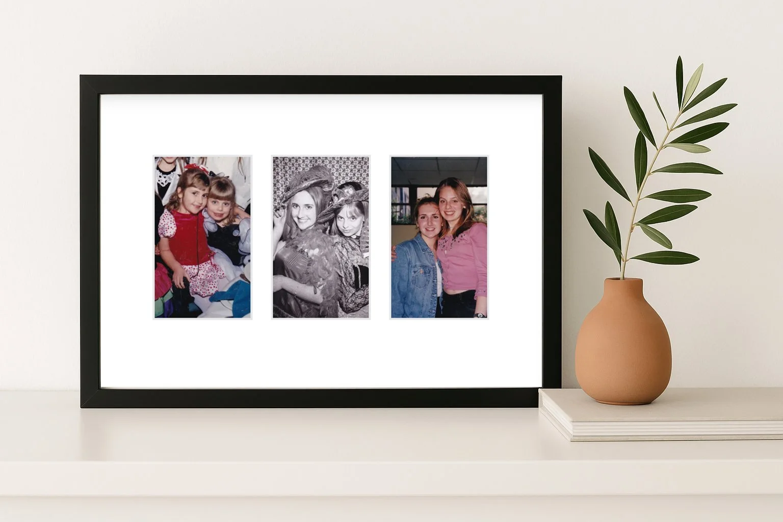 Framed photo collage featuring three pictures of two young girls at different ages, displayed on a white surface with a beige pottery vase holding a green plant nearby.