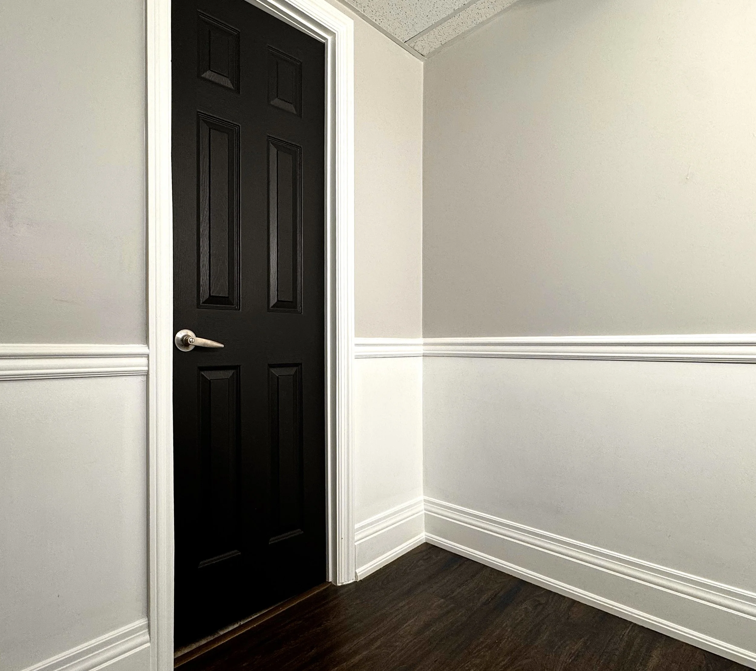 Hallway with black interior door white wainscoting and freshly painted grey walls