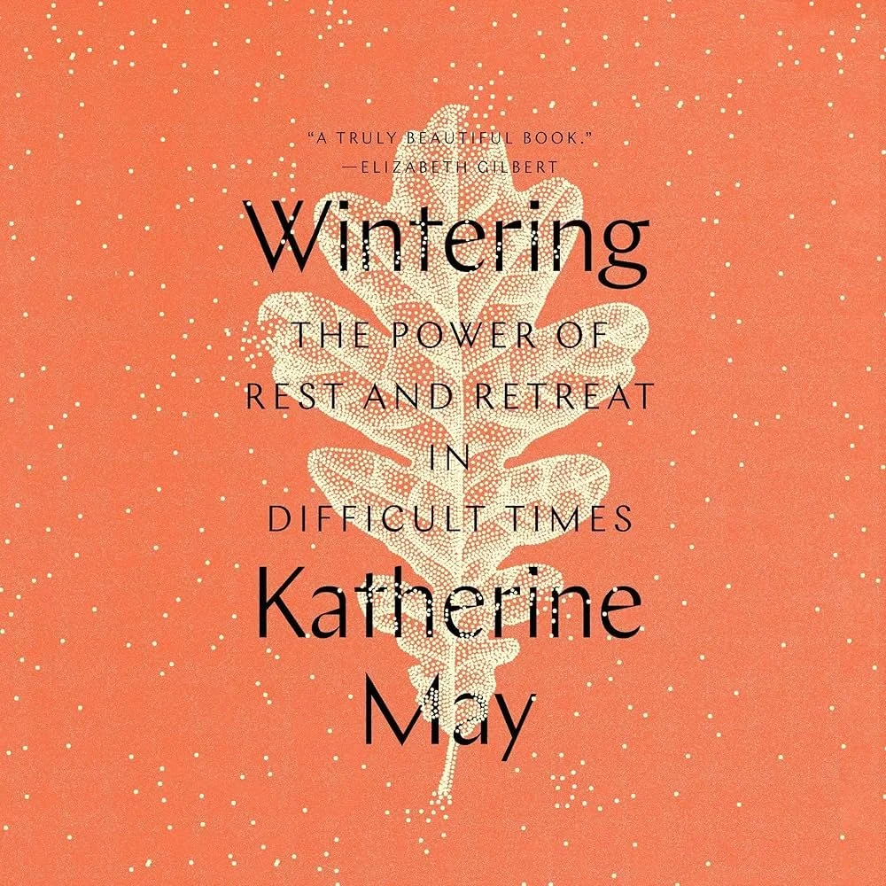 Book cover with orange background and white speckles, featuring a white leaf design, and black text with the title 'Wintering: The Power of Rest and Retreat in Difficult Times' by Katherine May, including a quote at the top.