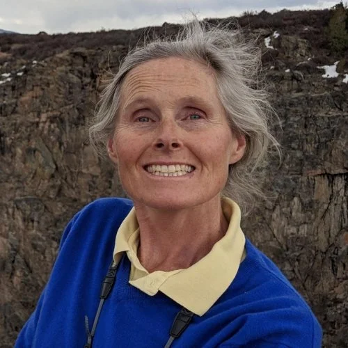 Lucy Bauer smiling, outdoors in front of a rocky hillside.