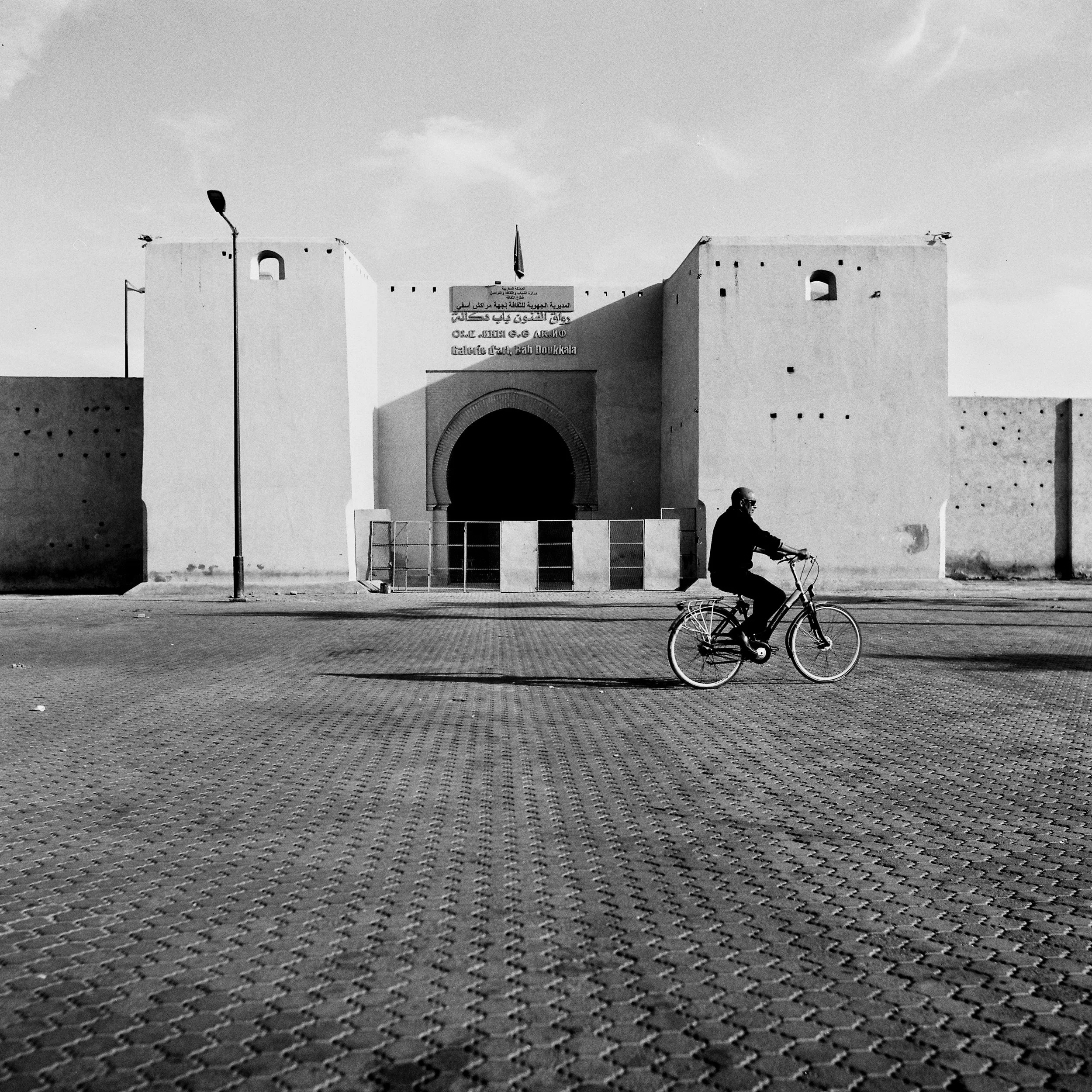 Man on bicycle in front of Galerie d'Art Bab Doukkala, Marrakech, Black & White