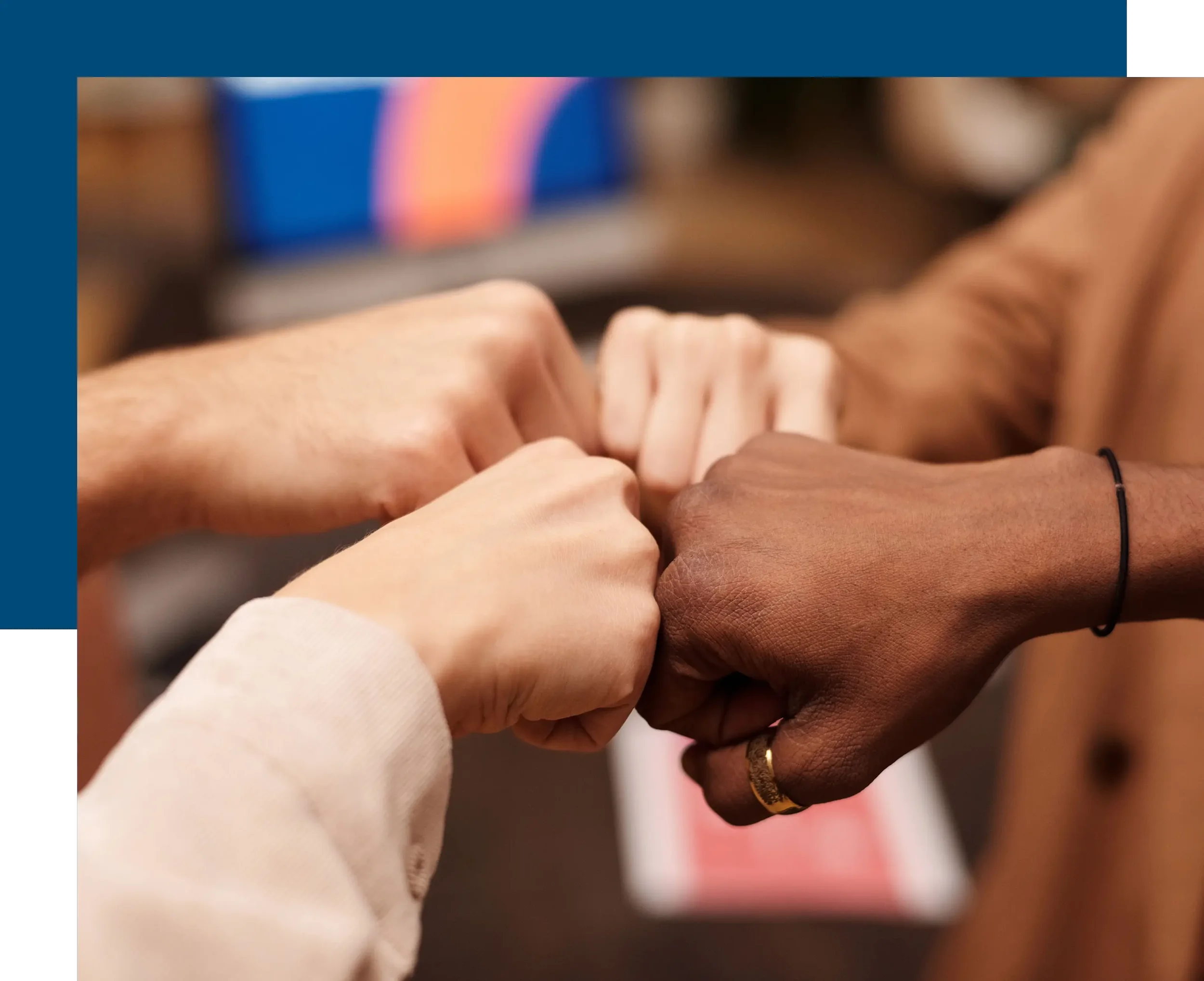 Four people bringing their fists together in a fist bump, symbolizing unity and teamwork.