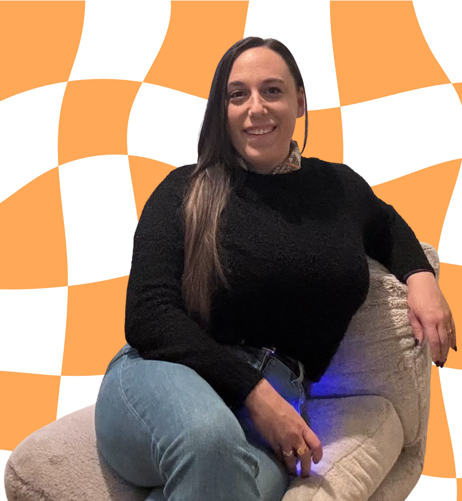 A woman with long dark hair smiling, sitting on a beige armchair with a colorful orange and white checkered background.