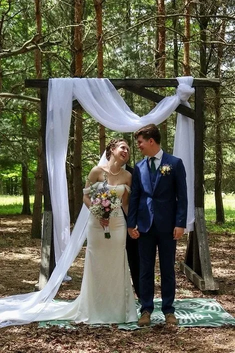 bride and groom under wedding arch with fabric