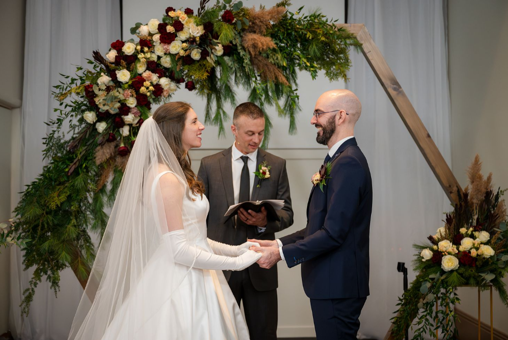 bride and groom under lush floral arch