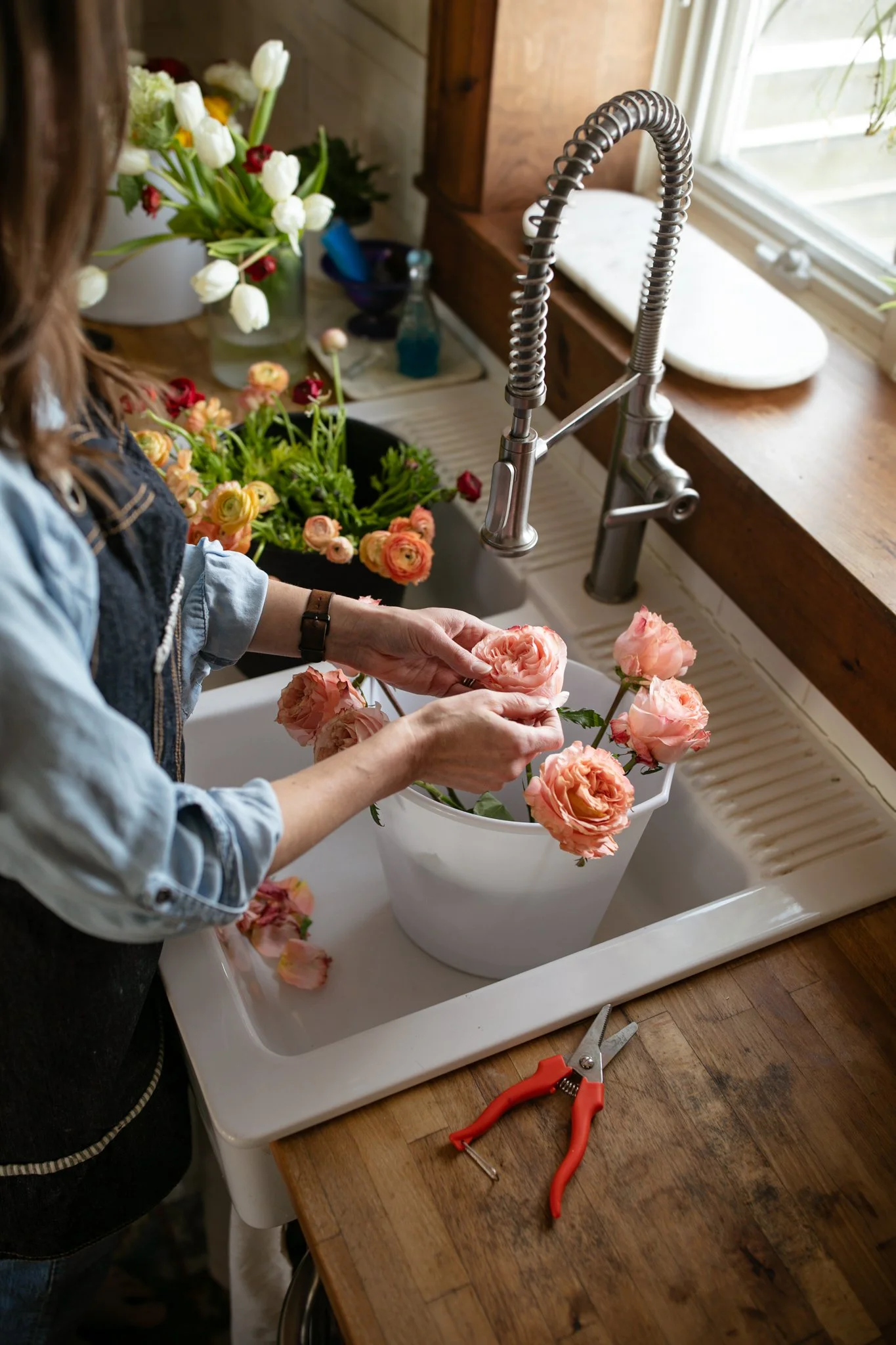 florist preparing blooms for drying standing at sink handling pink roses