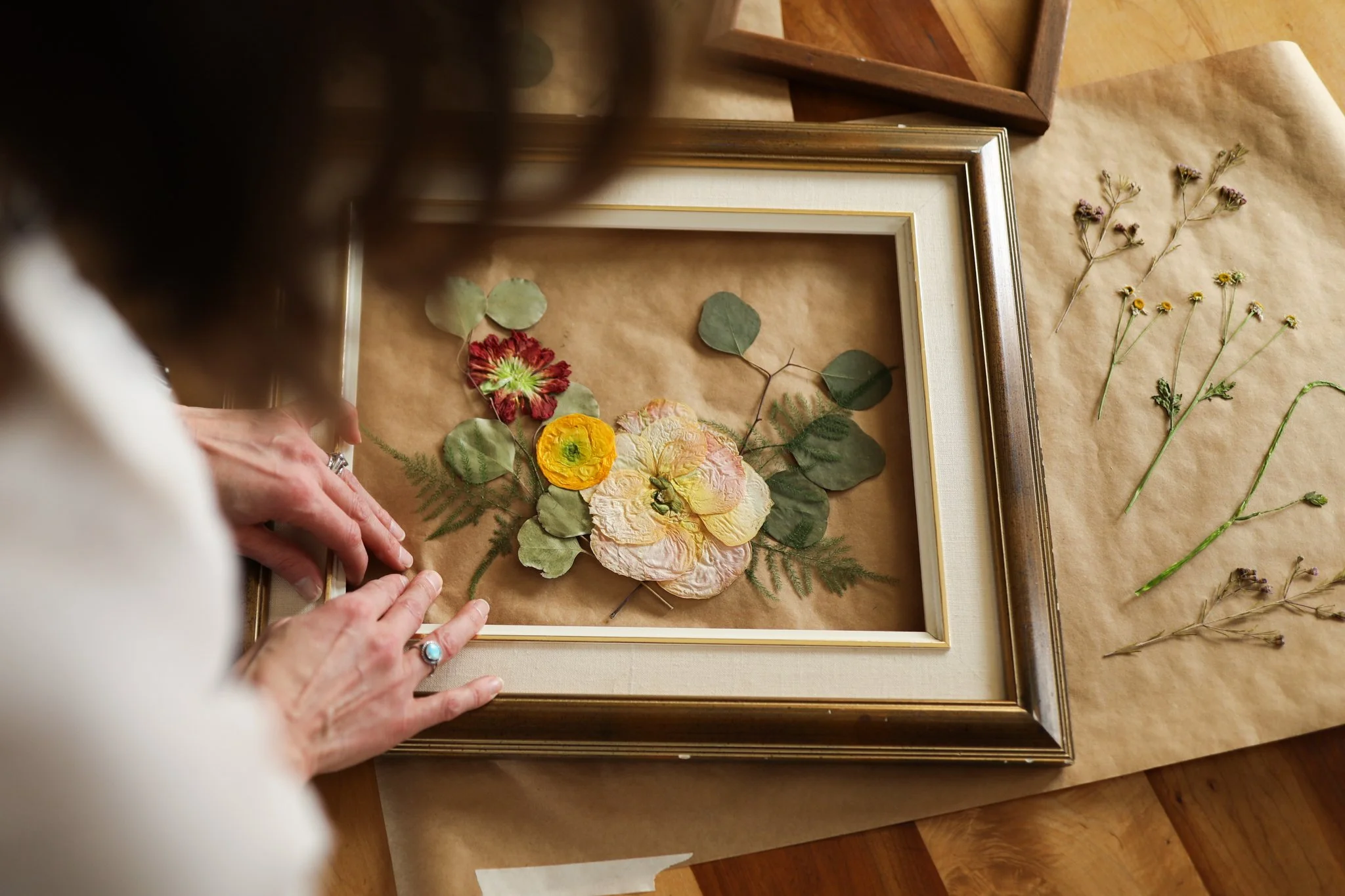 designer placing dried flowers in a frame