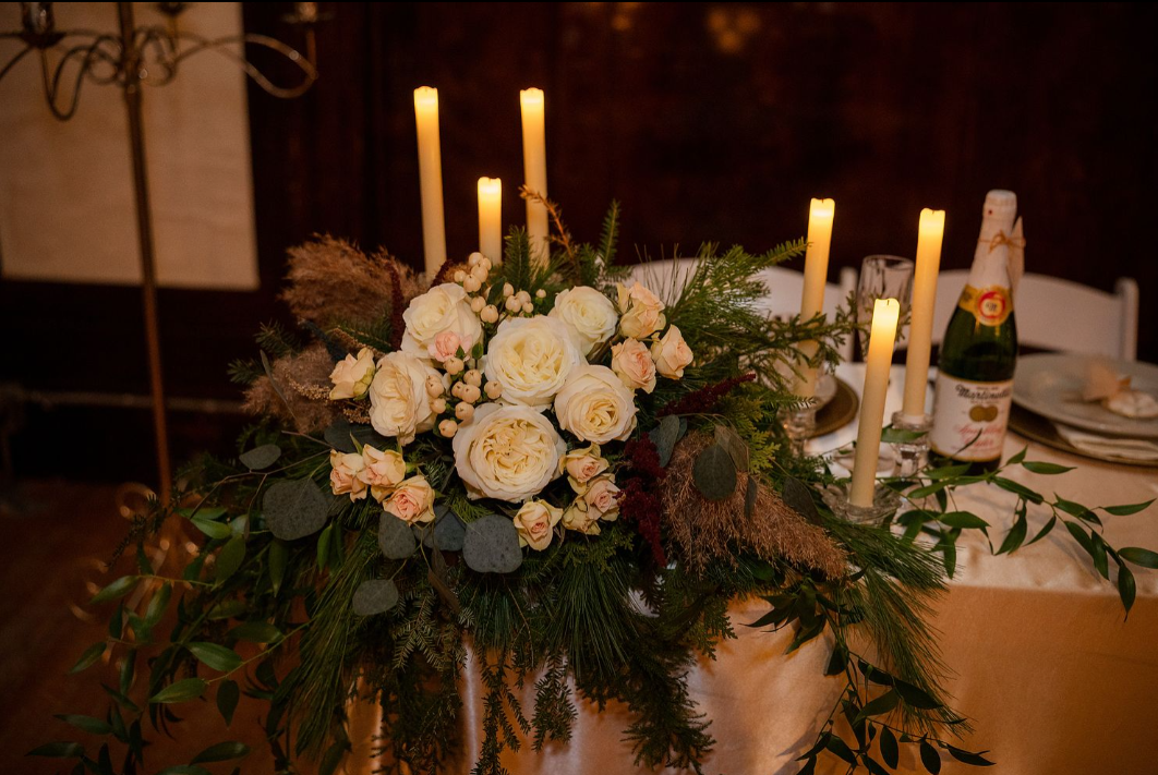 white floral arrangement and candles on sweetheart table