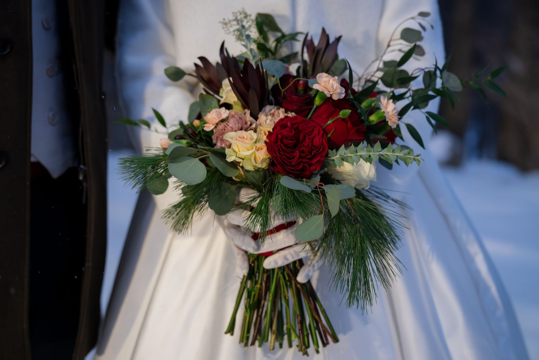 bridal bouquet with red roses vintage pink carnations and winter greenery