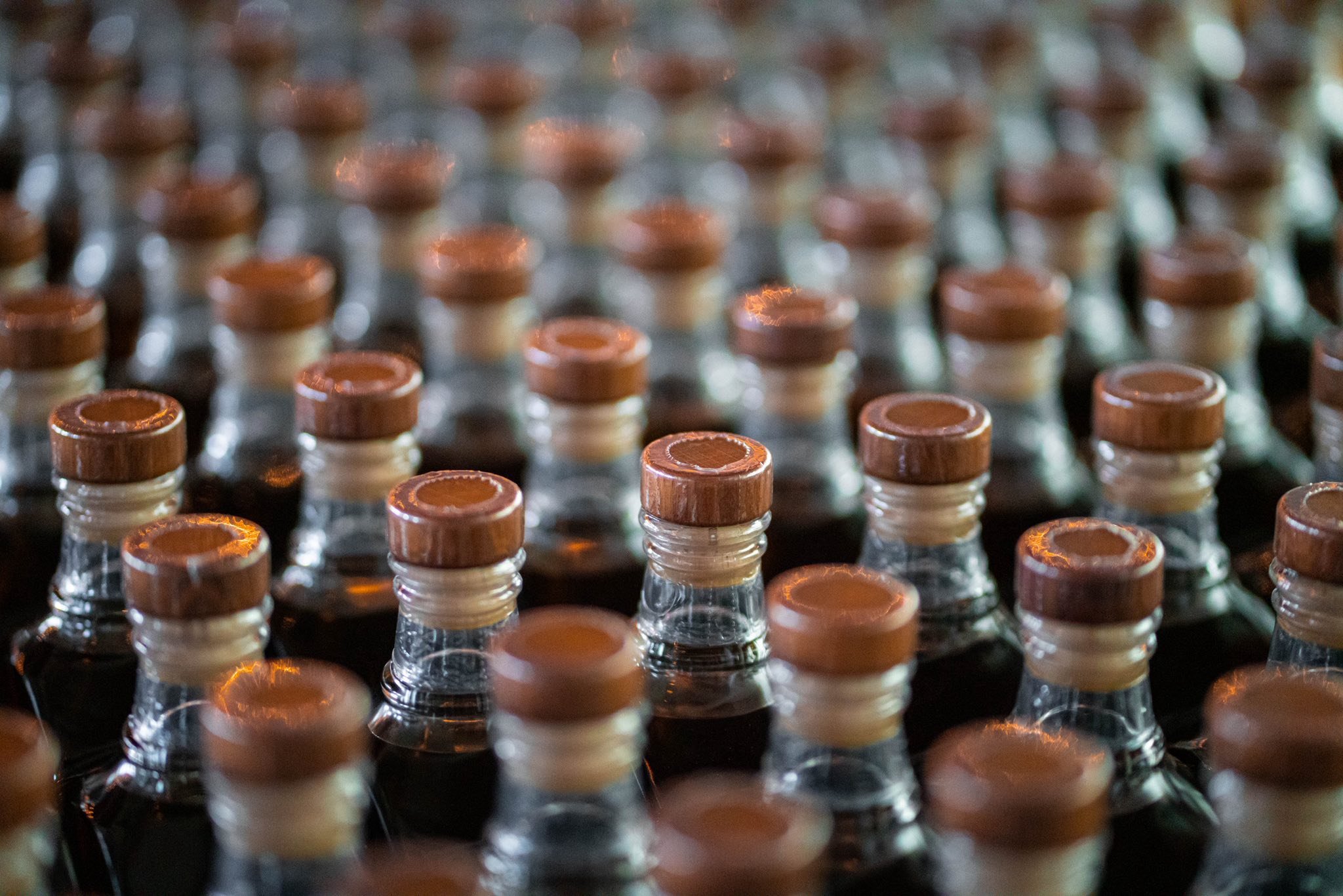 Close-up of glass bottles with brown caps arranged in rows.