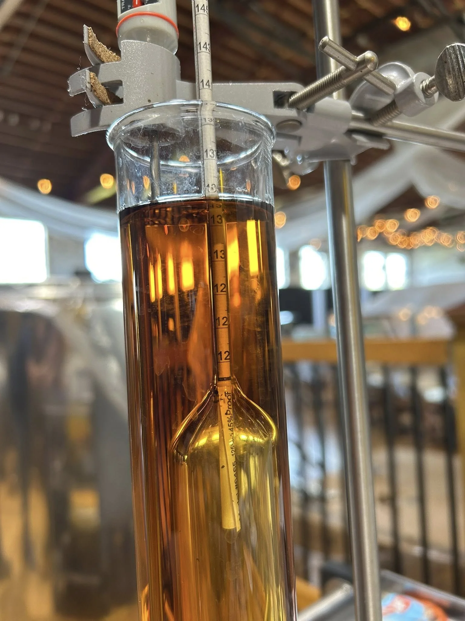 A laboratory setup with a glass column filled with amber-colored liquid, measuring around 14 centimeters, connected to a thermometer and other scientific apparatus.