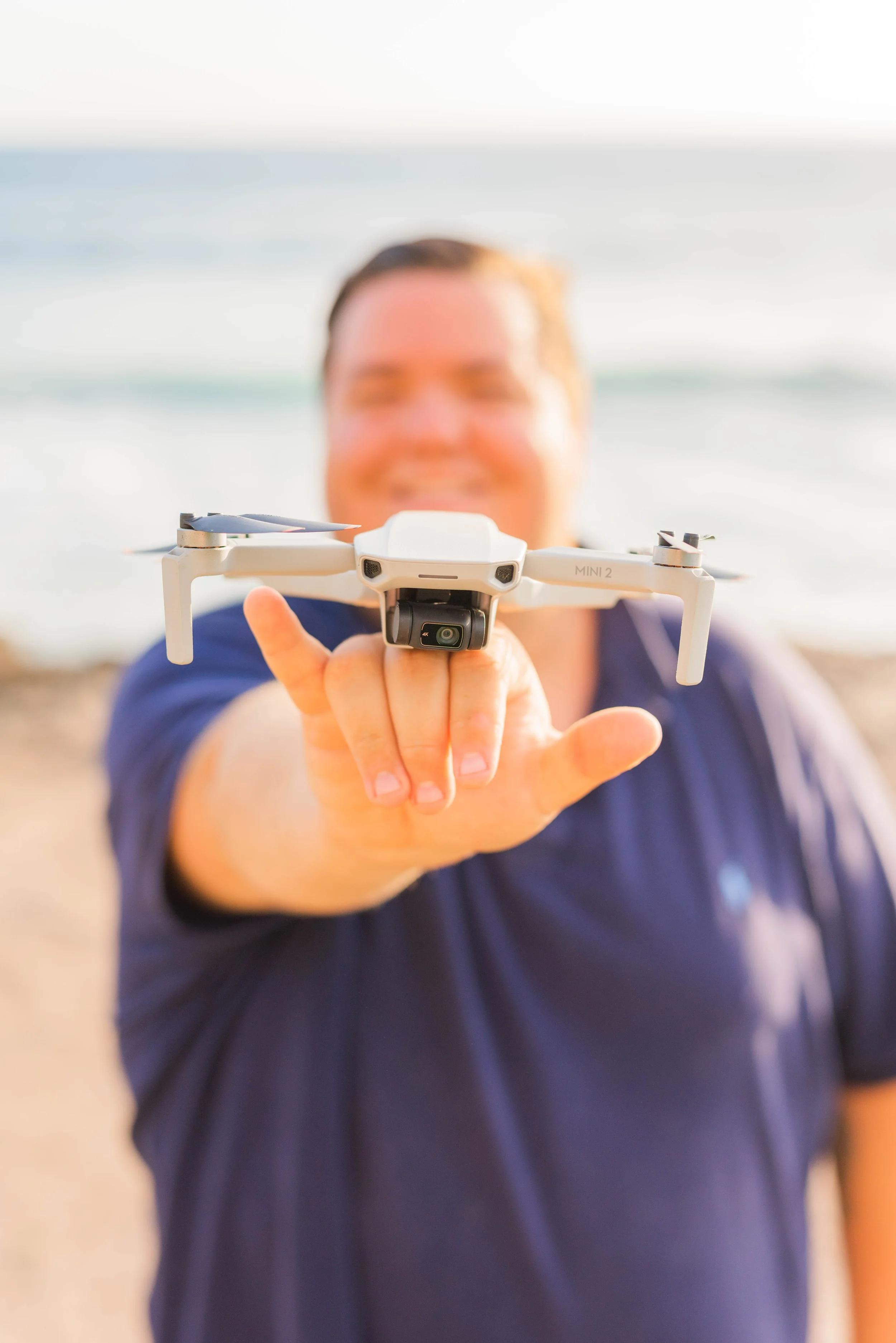 Man holding a drone towards the camera on the beach