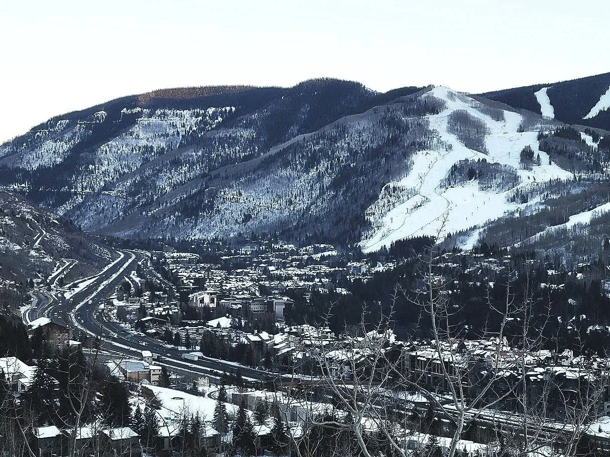 Snow-covered town at the base of a mountain with ski slopes and roads.