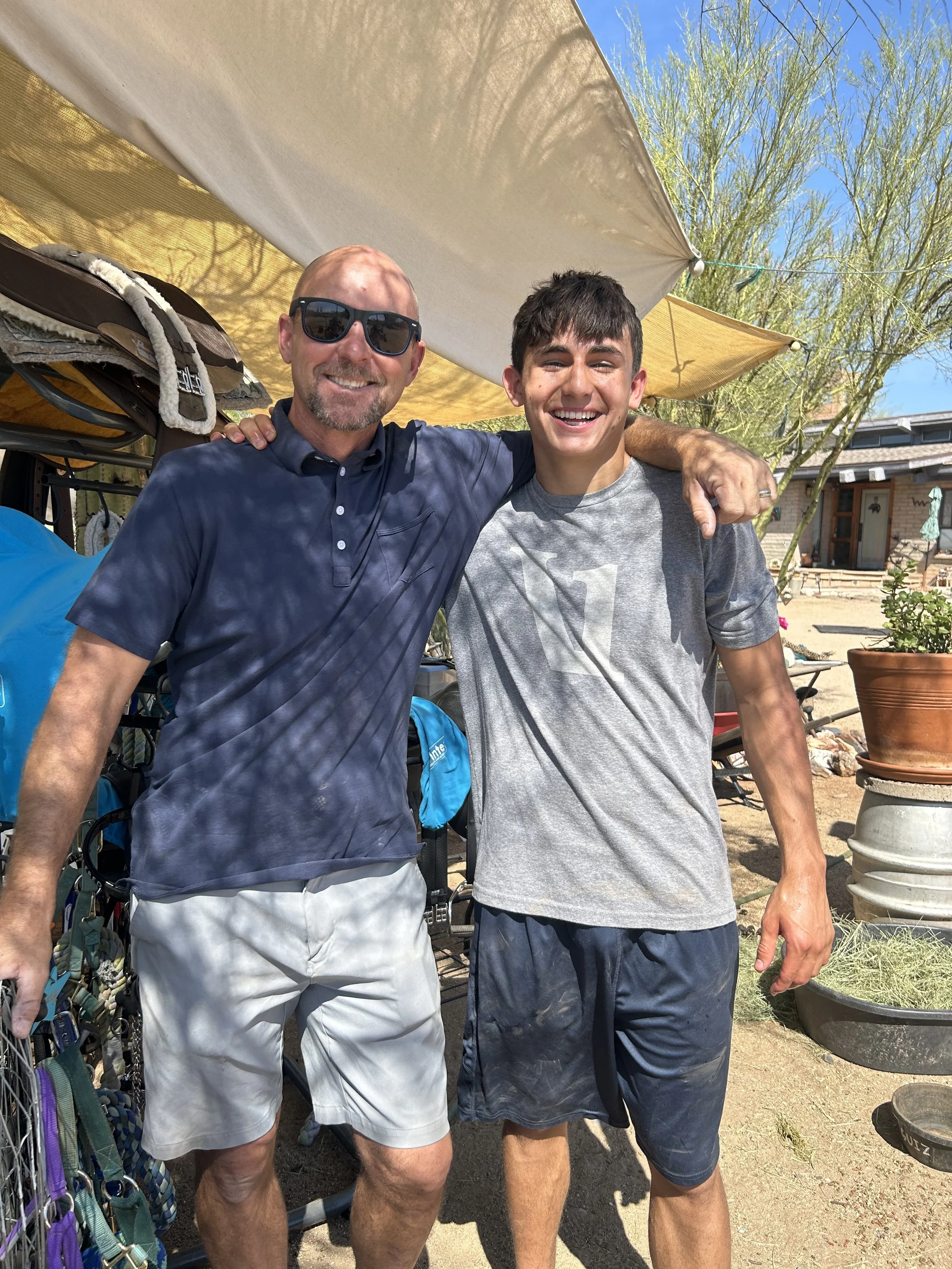 A father and son, both volunteers, smiling with their arms around each other.