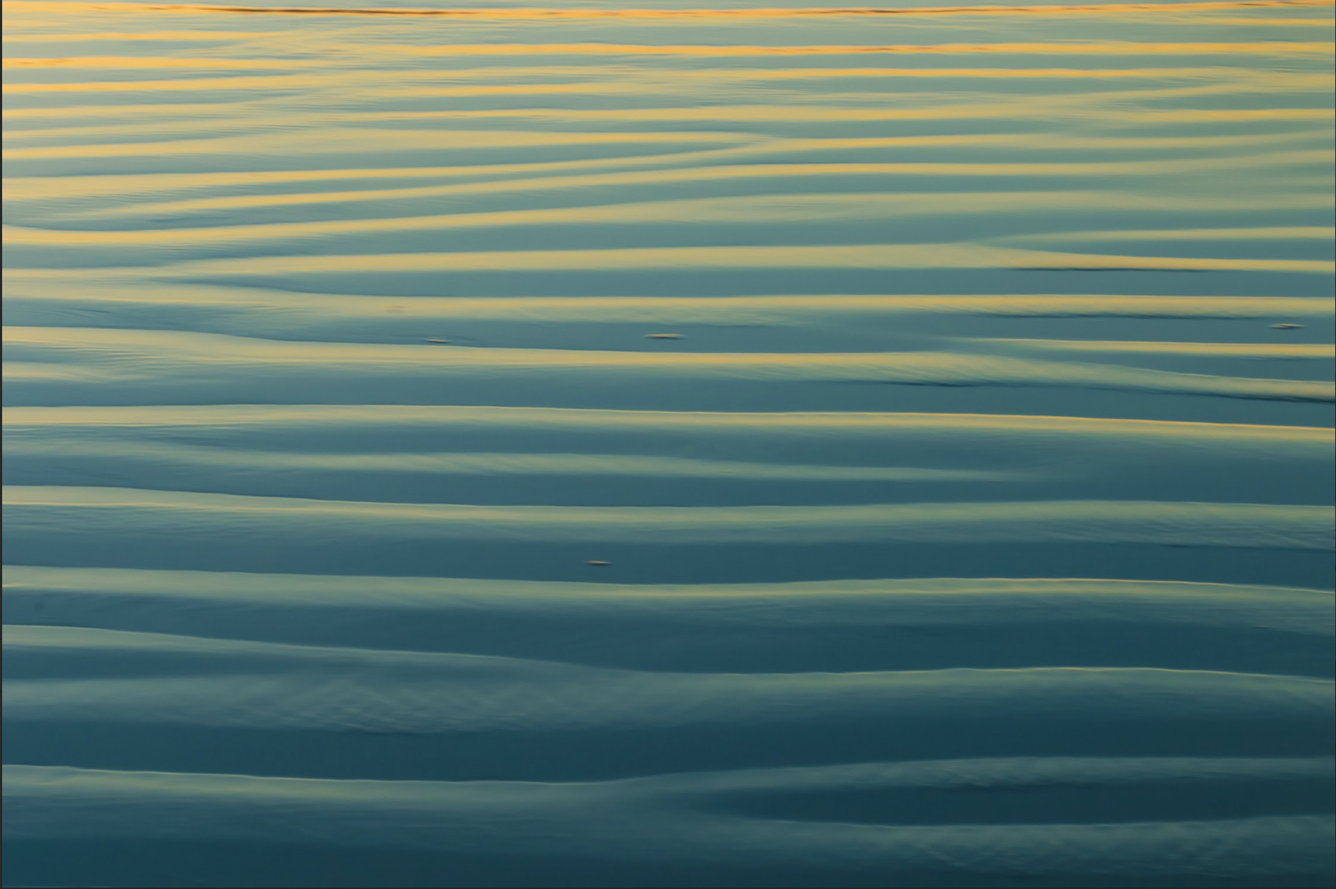 Beach sand reflecting the golden and blue hues of the sky during sunset or sunrise.