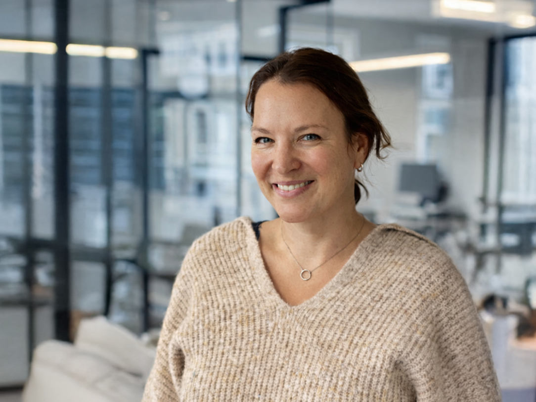 Kvinne smilende i kontorlandskap med store vinduer