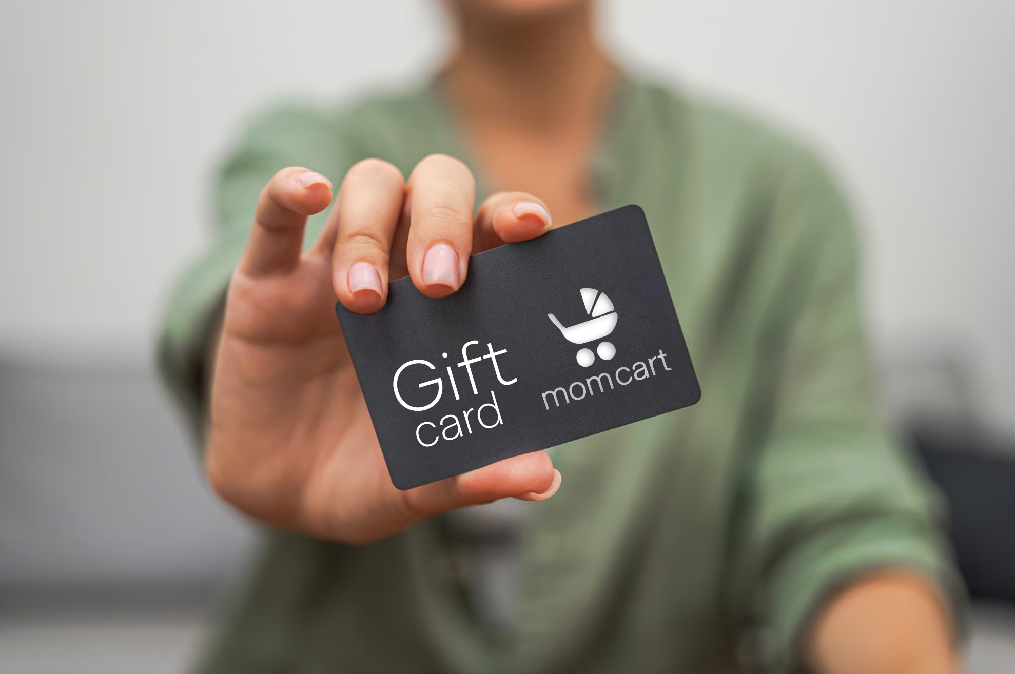 Person holding a black gift card with a white logo and the words 'Gift card' and 'momcarta' on it.