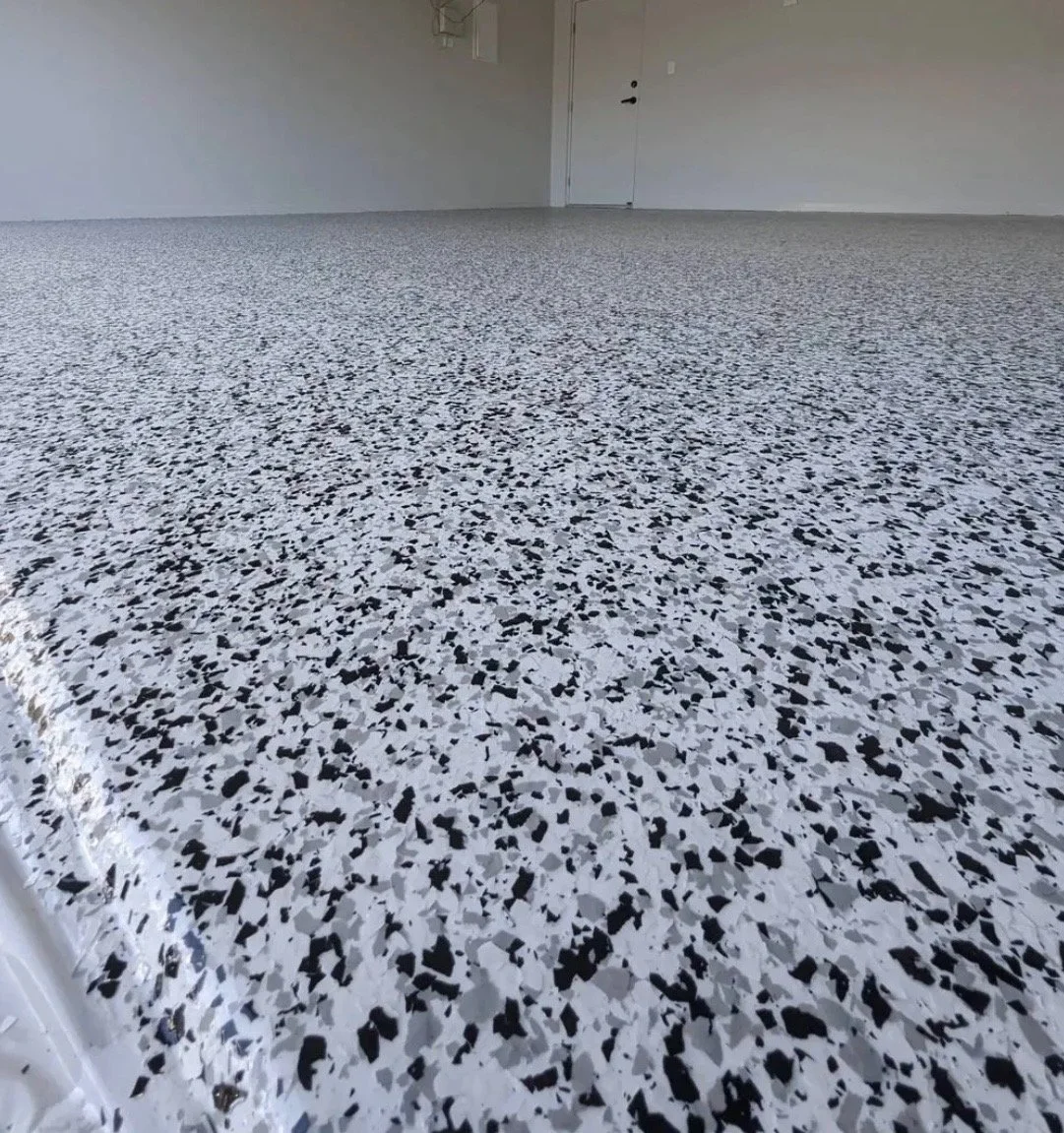 Empty room with terrazzo flooring, white walls, and a door in the background.