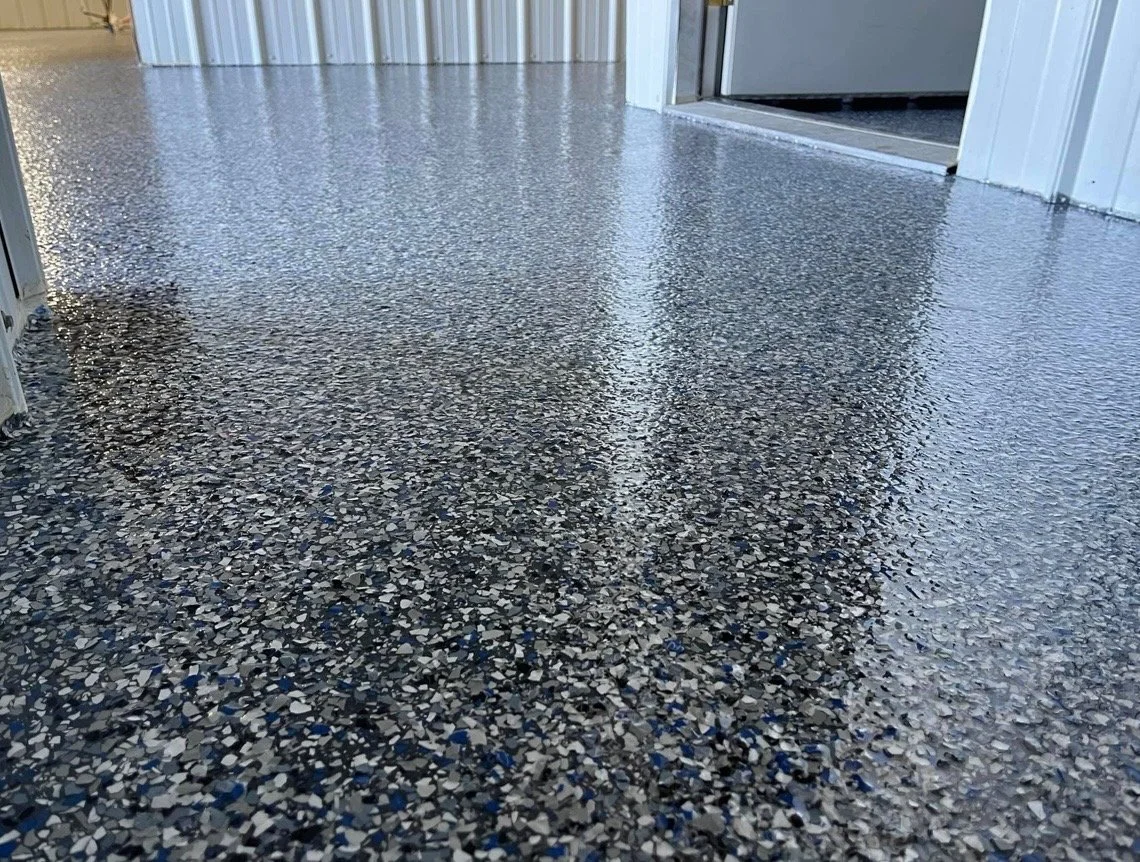 Close-up of a polished, speckled epoxy floor in a building hallway with white walls.