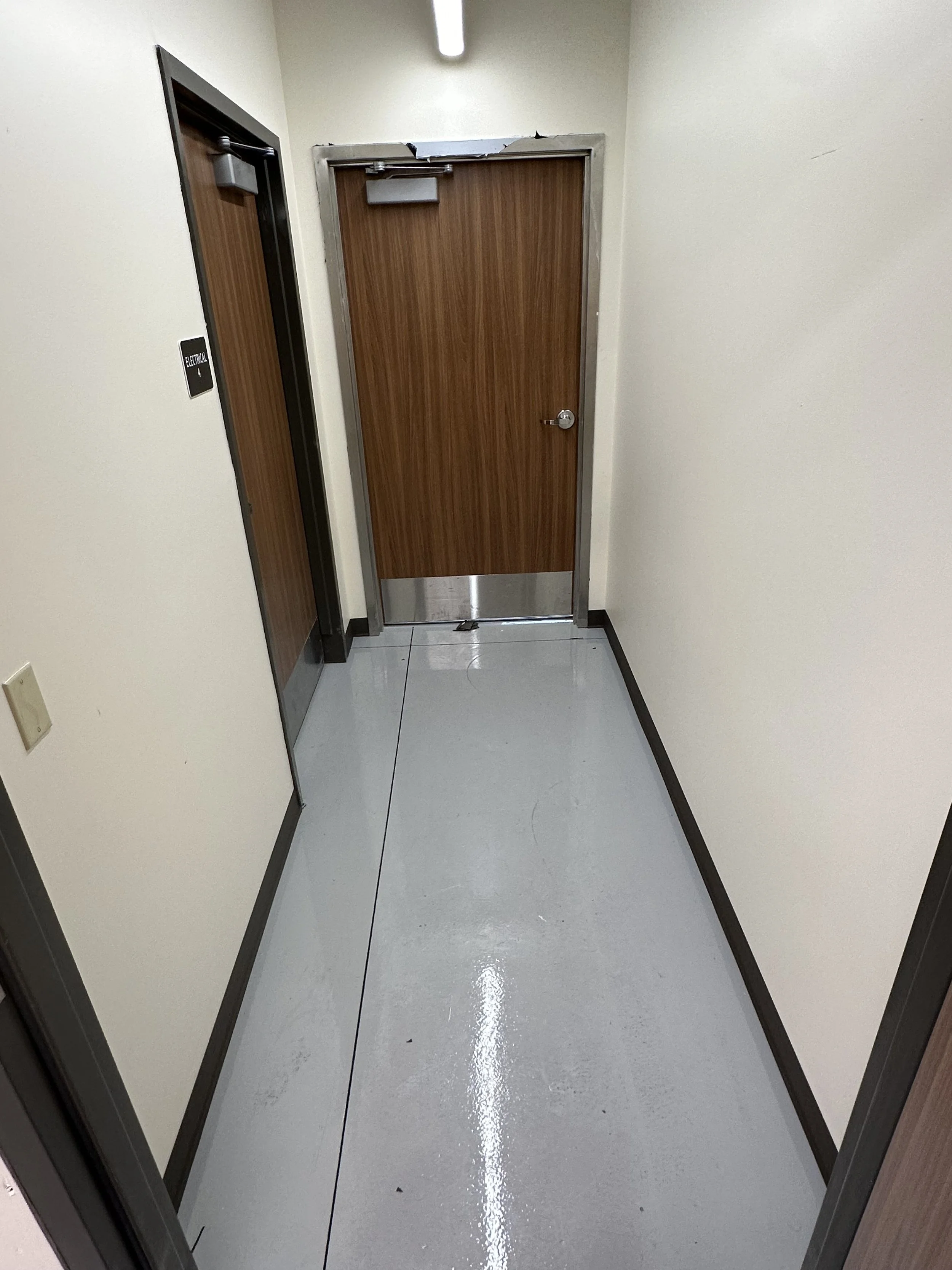 Hallway with an elevator door on the left and a wooden door at the end of the hall.