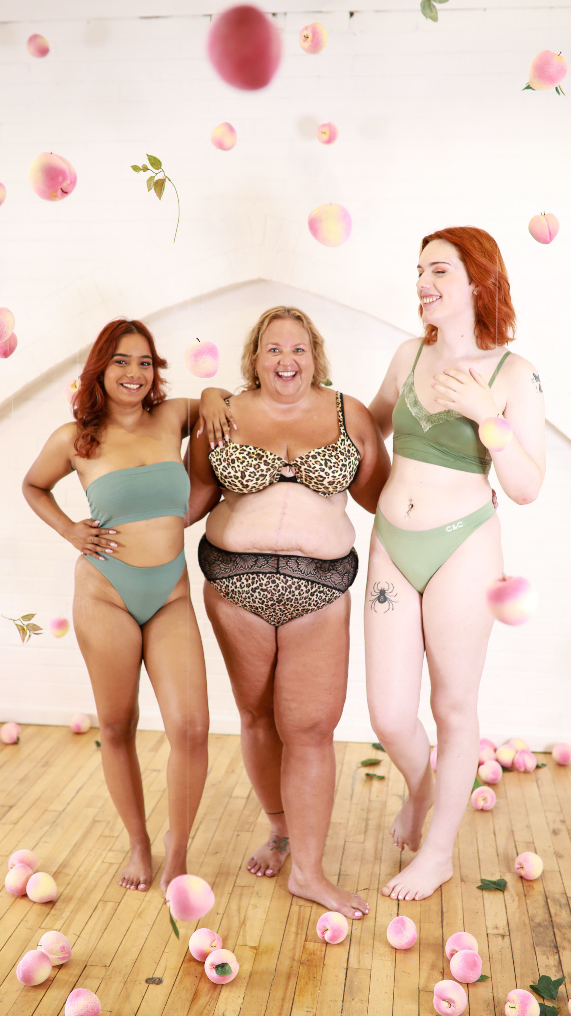 Three women of varying body types stand together happily, embracing their bodies with pride.