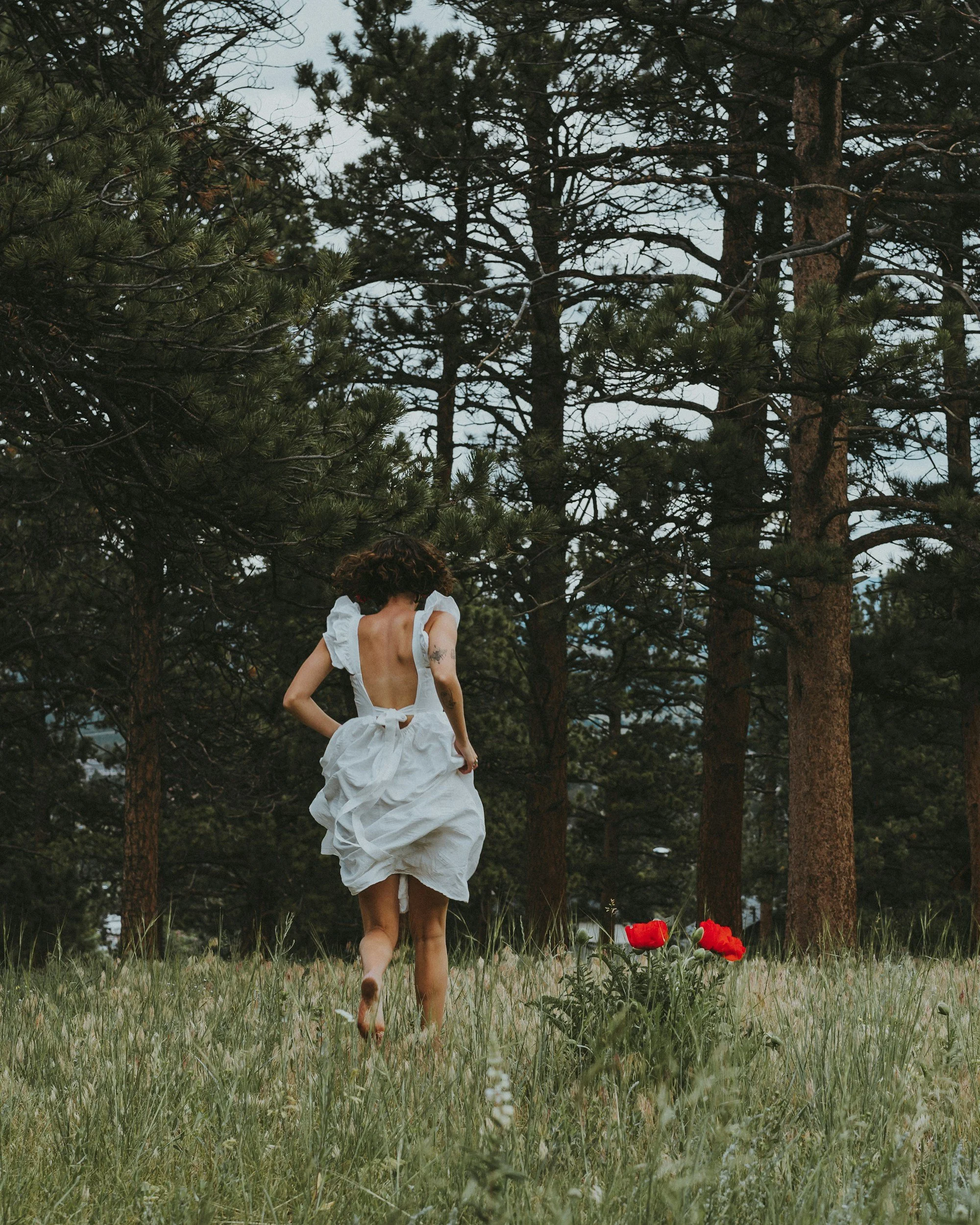 A woman runs freely through the woods.